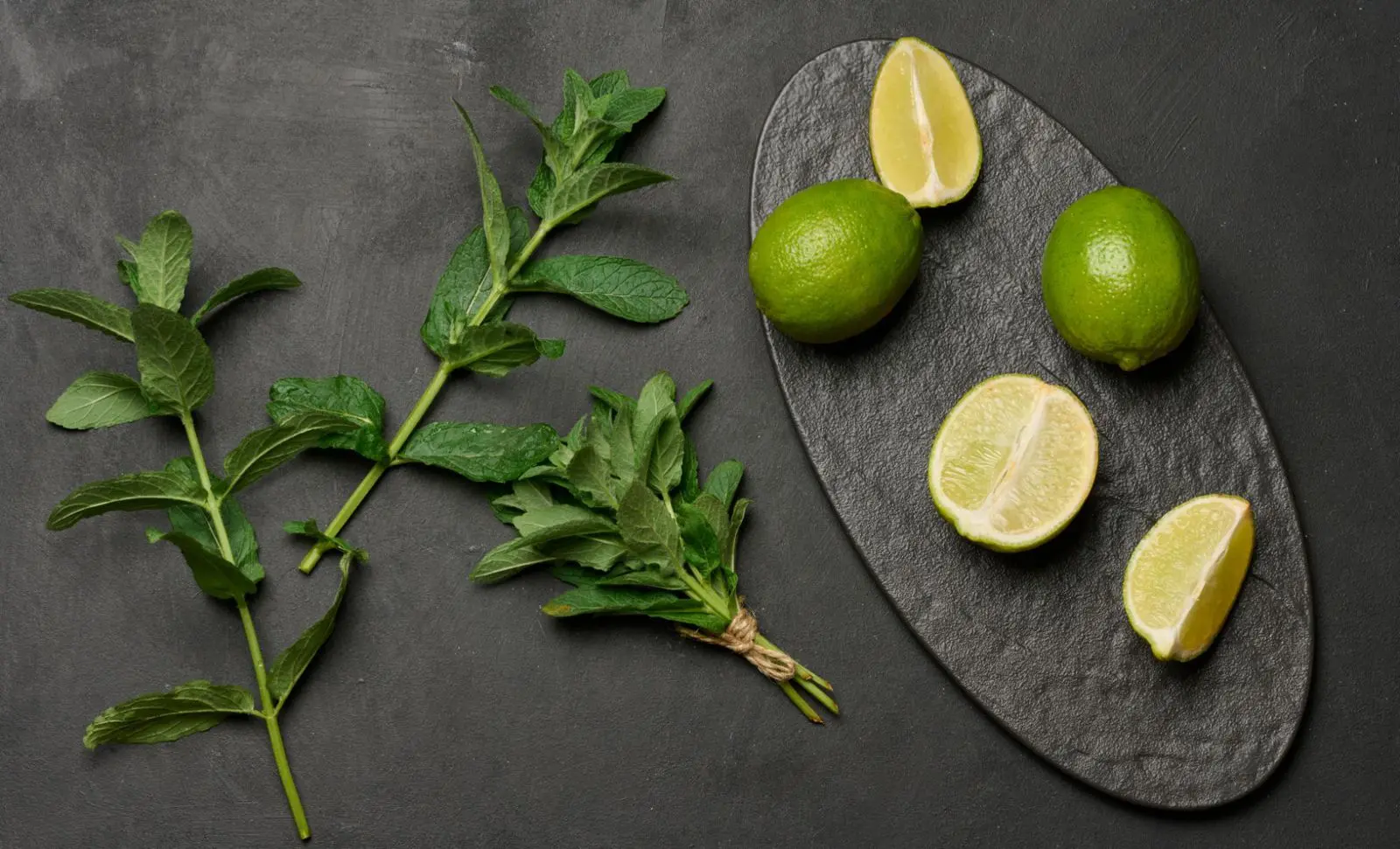 Fresh mint and halved limes on slate